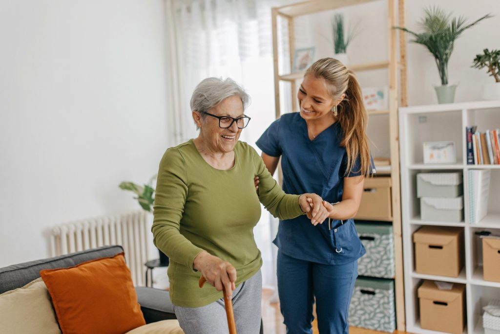 infirmière à domicile aide une femme âgée à se lever et marcher