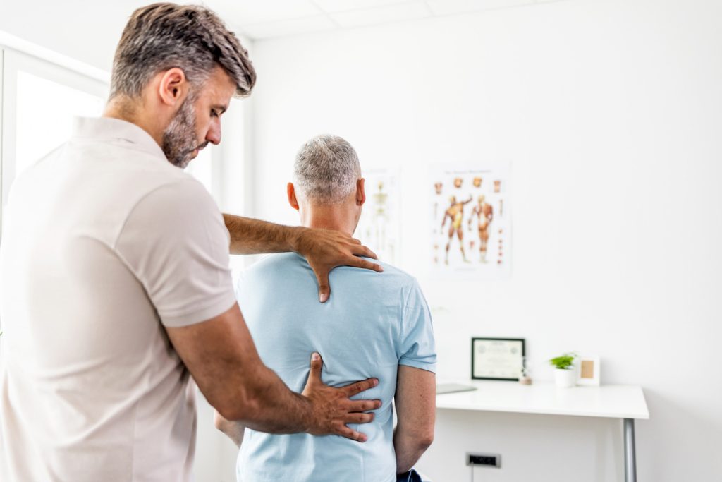 homme se faisant ausculter le dos chez un ostéopathe chiropracteur
