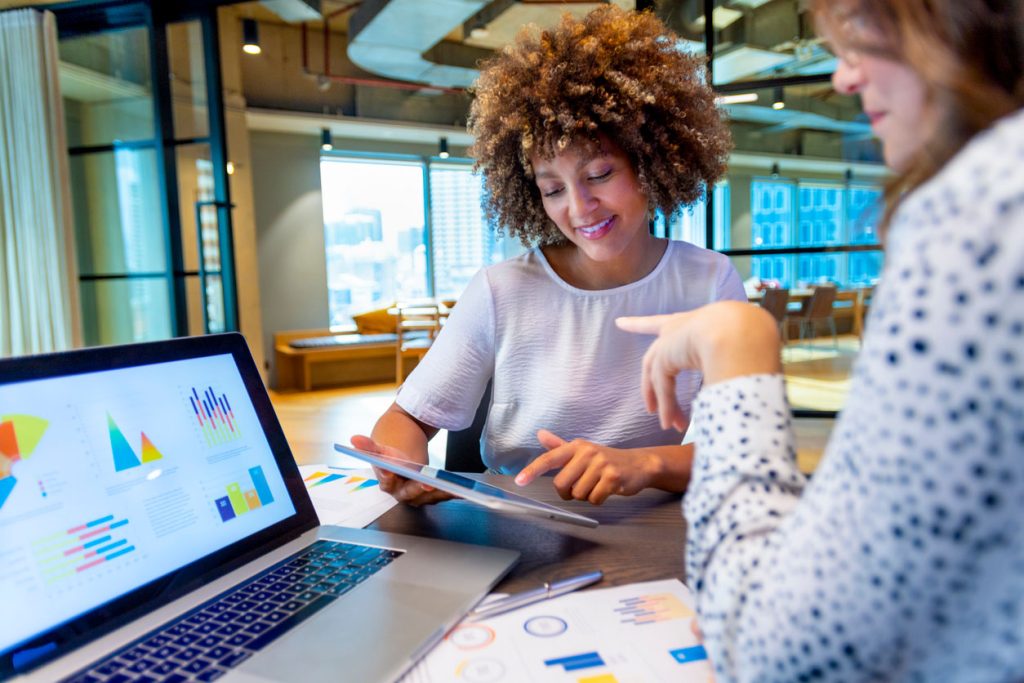 deux femmes regardant des statistiques sur une tablette